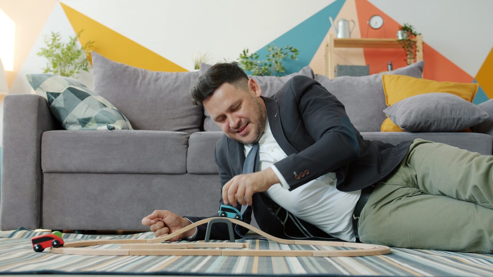 Man in suit lying on floor with toy train